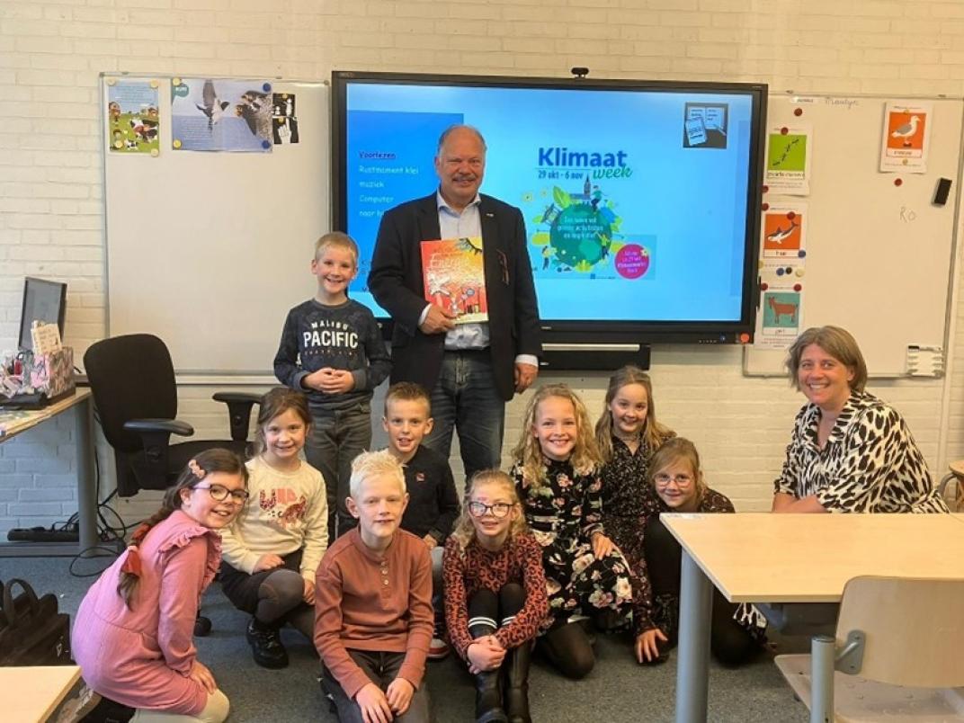 Wethouder houdt boek vast met kinderen op zich heen